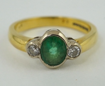 A modern 18ct gold, emerald and diamond set three stone ring, size N, gross weight 4.4 grams. Condition - fair